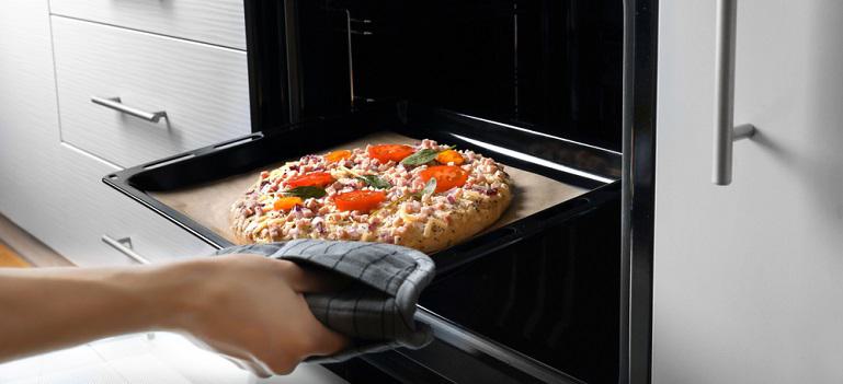 putting pizza in oven