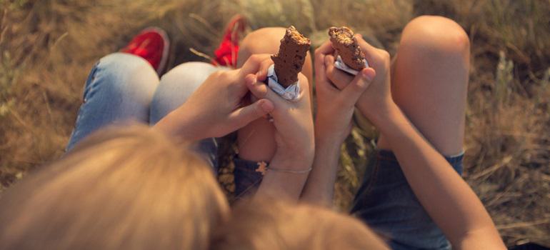 two children, a boy and a girl are sitting on the grass, resting and eating energy bars, a view from above