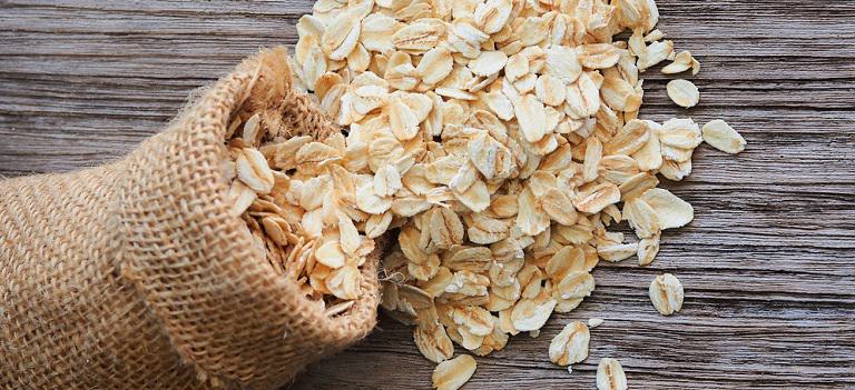 Old fashioned rolled oats in burlap bag on wood table