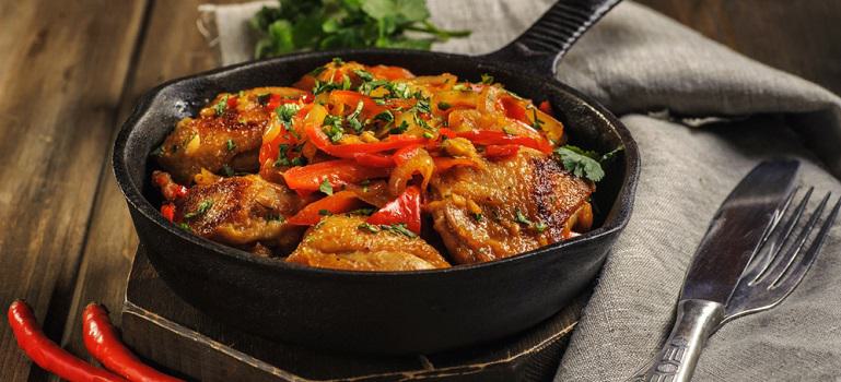 Fried chicken in spicy sauce with vegetables. Cooked in a cast iron pan