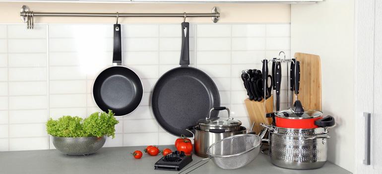 Set of clean cookware, utensils and products on table in modern kitchen