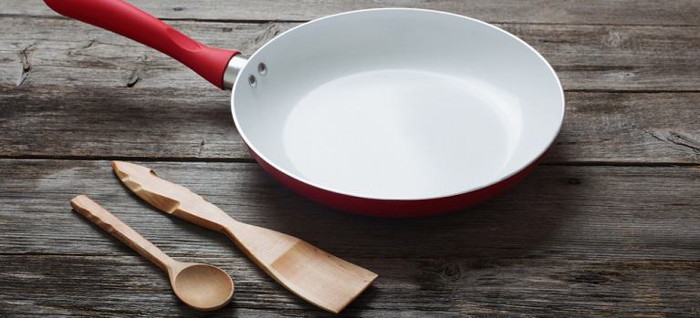 red ceramic frying pan on old wooden background