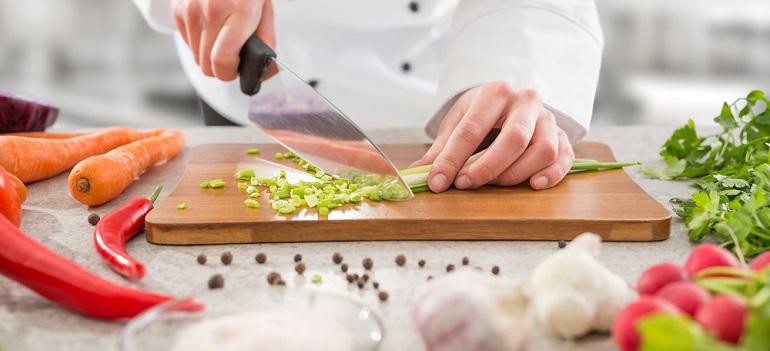 Chef cutting vegetables on a wooden board