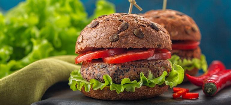 Veggie burger made from quinoa, beans, peanut sauce, green salad, hot peper and tomatoes