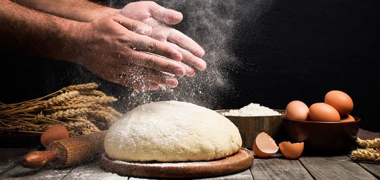 Man slaps flour over the dough