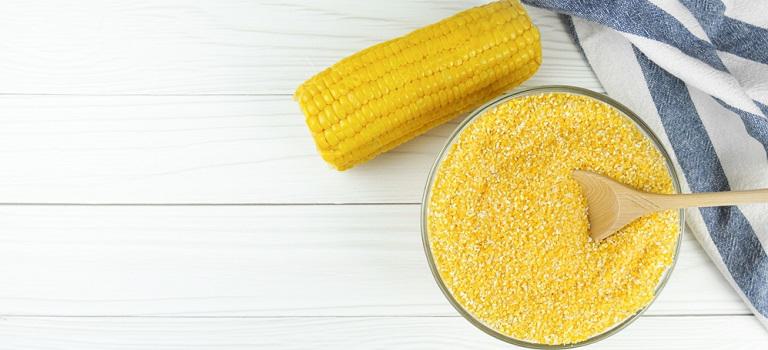 Corn grits in a glass bowl with a wooden spoon
