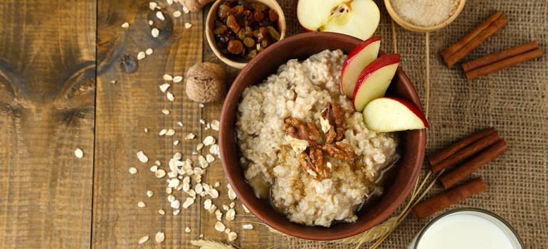 Tasty oatmeal with nuts and apples on wooden table