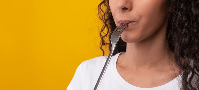 hungry young lady holding fork in her mouth